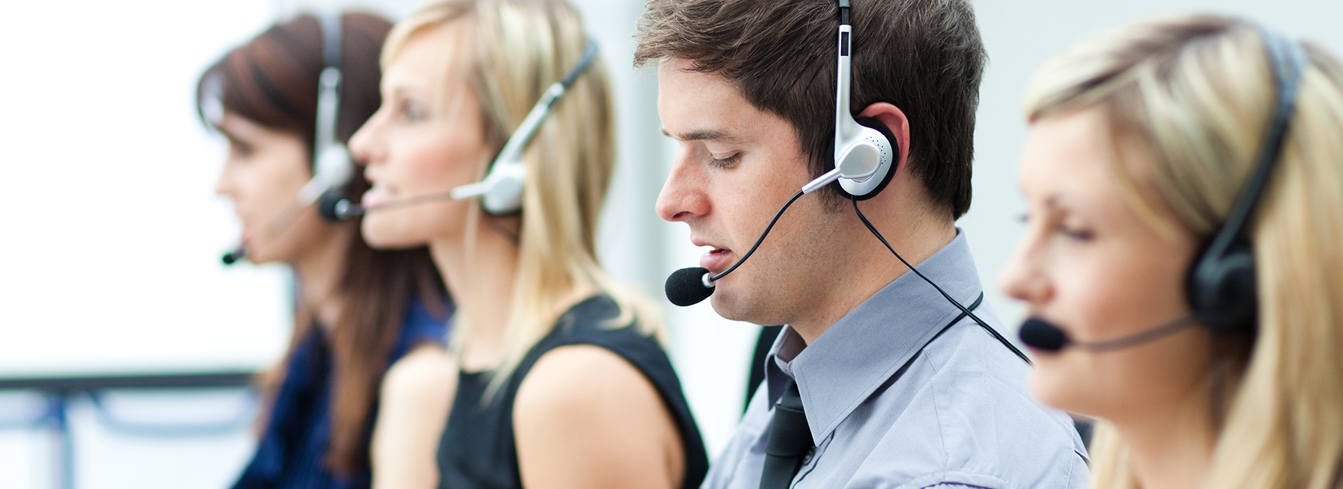Attractive young man working in a call center with his colleagues
