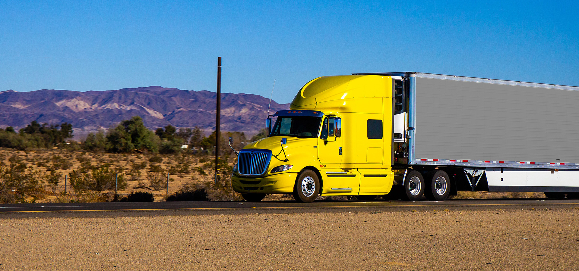 Semi-remorque jaune roulant en direction de la caméra sur une route du Nevada