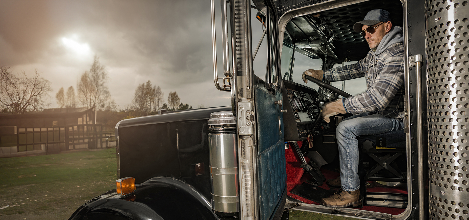 Caucasian Trucker in His 40s Inside American Semi Truck Tractor. Ground Cargo Theme.