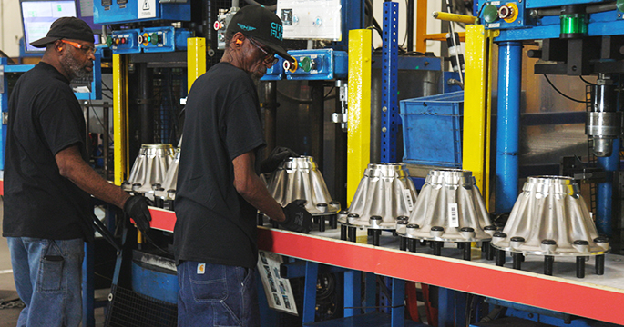 Production line of aluminum Wheel Ends being made with 2 employees checking the quality